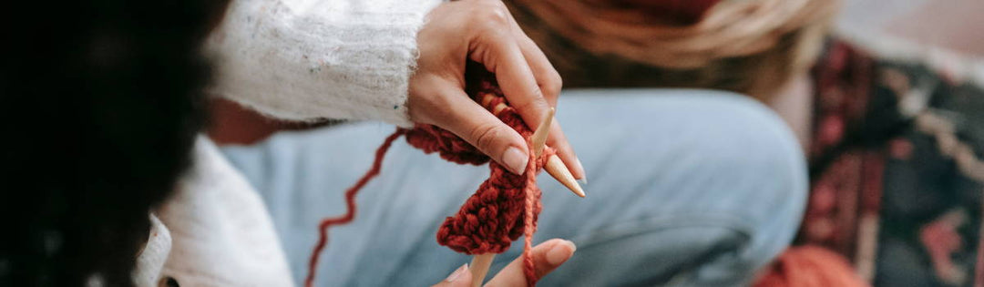 Eine Frau strickt englisch mit rotem Garn.